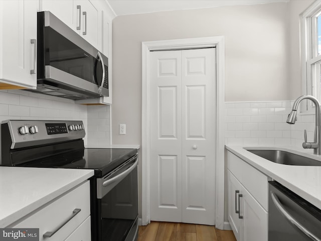 kitchen with appliances with stainless steel finishes, white cabinetry, and sink