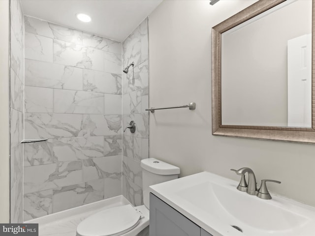 bathroom with tiled shower, vanity, and toilet