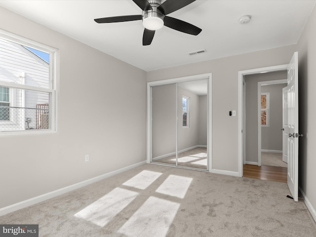 unfurnished bedroom with light colored carpet, ceiling fan, and a closet