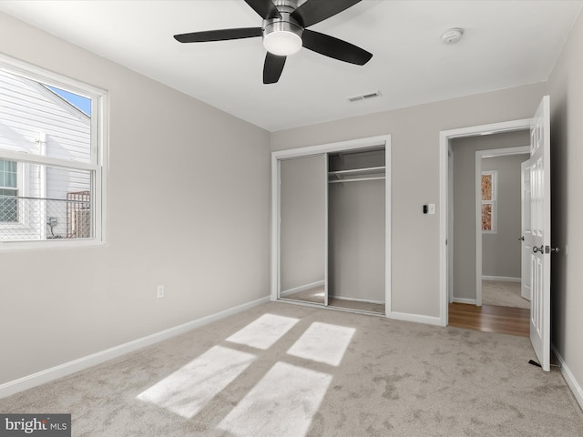 unfurnished bedroom featuring ceiling fan, a closet, and light carpet