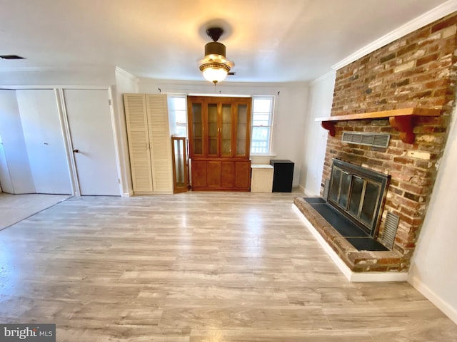 unfurnished living room with a brick fireplace, light wood-type flooring, and ornamental molding