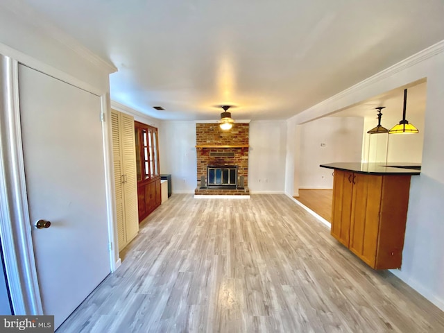 unfurnished living room with a brick fireplace, light wood-type flooring, and crown molding