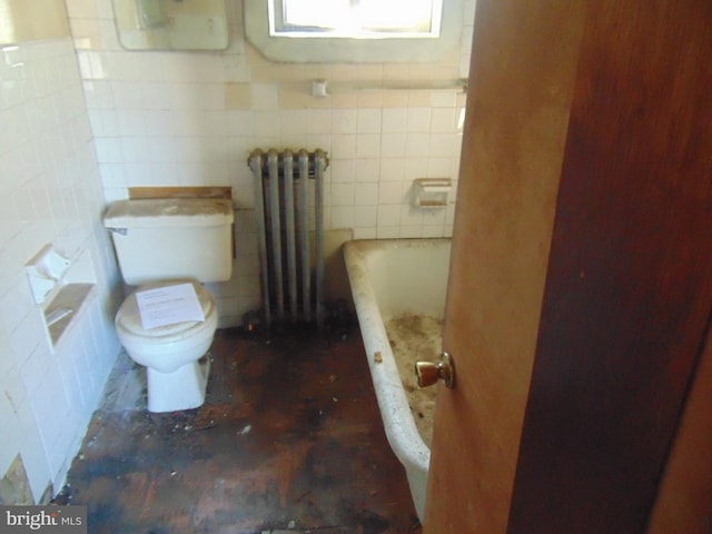 bathroom with tile walls, toilet, radiator heating unit, and a tub to relax in