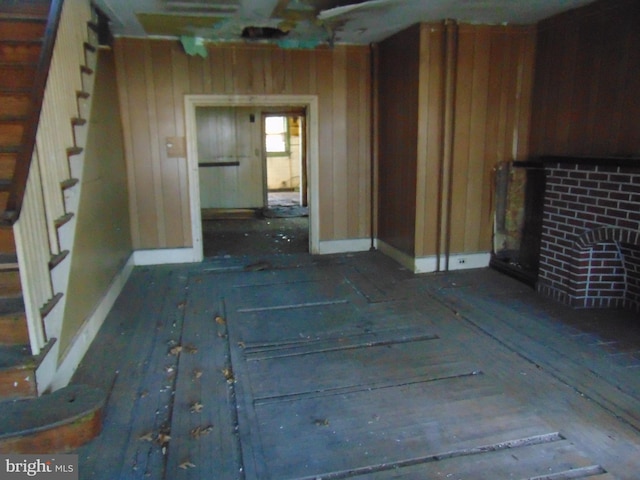 unfurnished living room featuring wooden walls