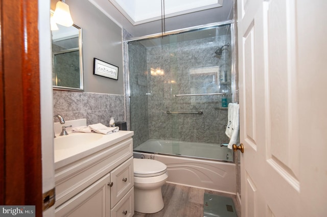 full bathroom with enclosed tub / shower combo, vanity, a skylight, tile walls, and hardwood / wood-style flooring