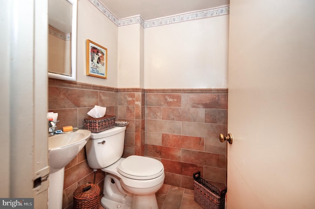 bathroom featuring toilet, tile patterned flooring, and tile walls