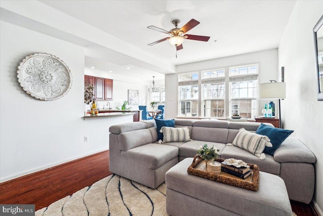 living room featuring hardwood / wood-style flooring, sink, and ceiling fan with notable chandelier