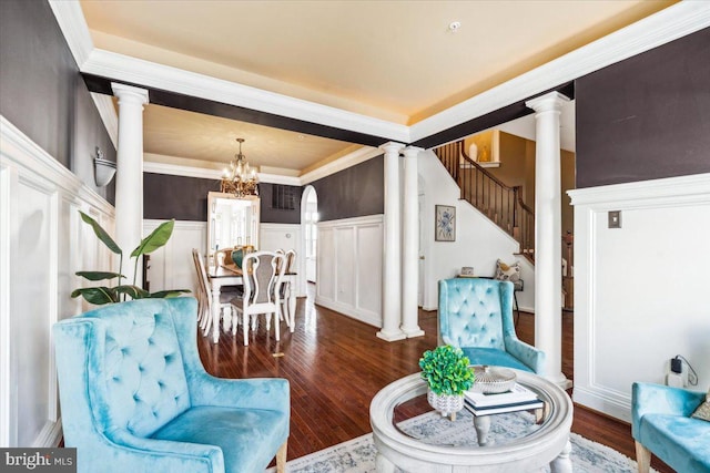 living area with decorative columns, crown molding, dark hardwood / wood-style floors, and a notable chandelier