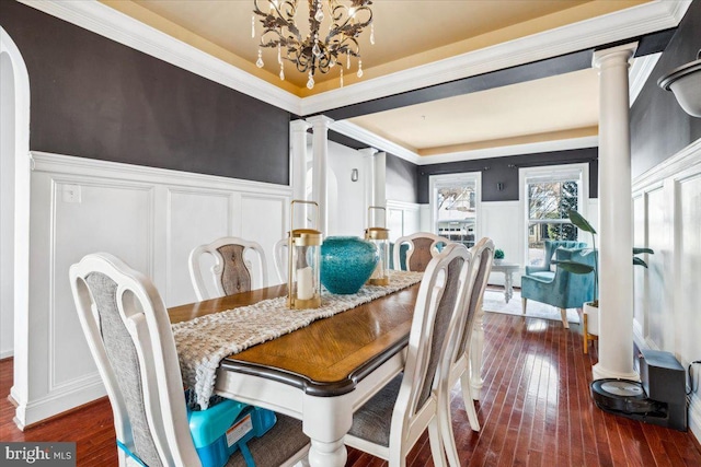 dining room with ornamental molding, dark hardwood / wood-style flooring, decorative columns, and a notable chandelier