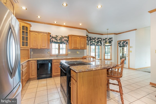 kitchen featuring light tile patterned floors, black appliances, a breakfast bar area, and a sink