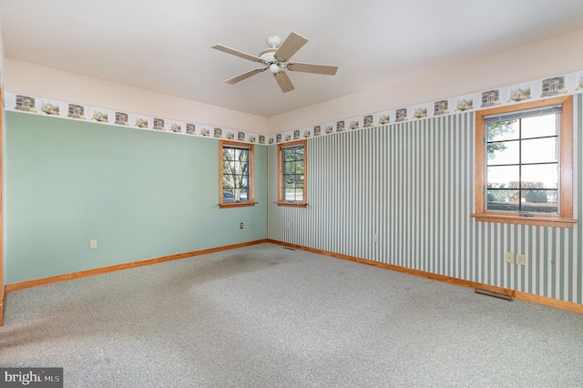 carpeted spare room featuring visible vents, a ceiling fan, and baseboards