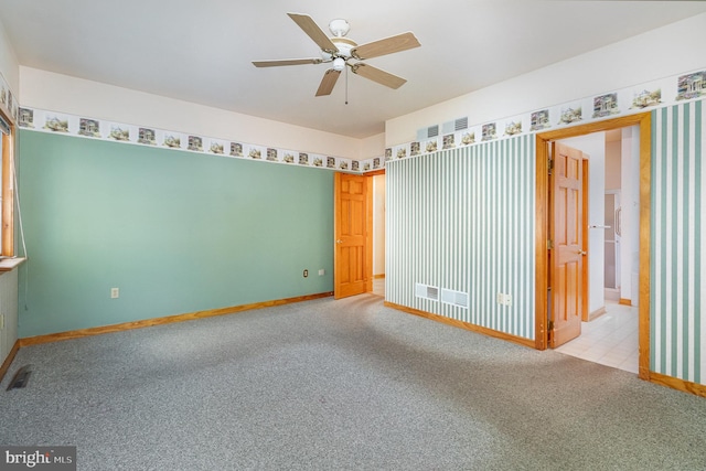 carpeted empty room with visible vents, baseboards, and ceiling fan