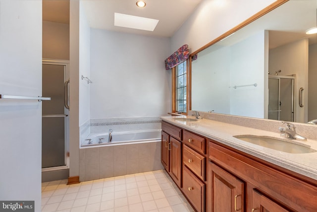 bathroom with a skylight, a shower stall, a garden tub, and a sink