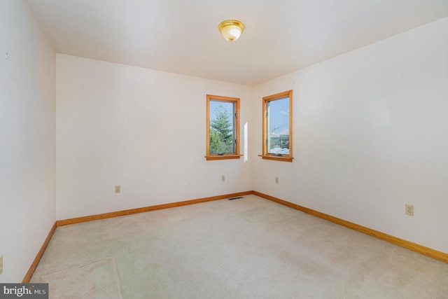 empty room featuring light carpet and baseboards