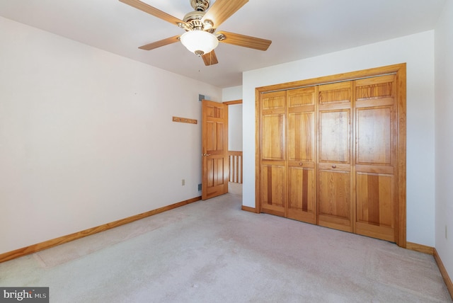 unfurnished bedroom featuring light carpet, a closet, a ceiling fan, and baseboards