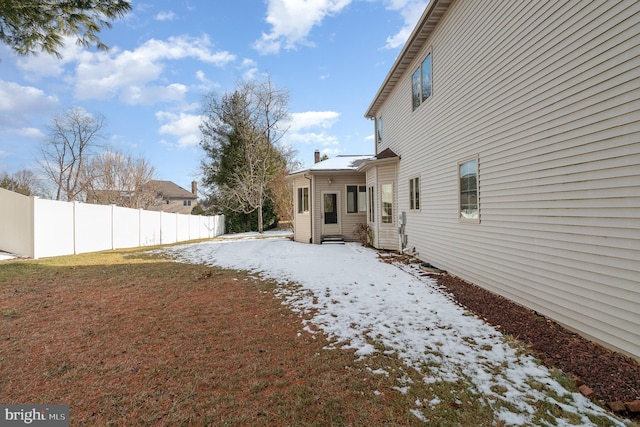 yard covered in snow featuring entry steps and fence