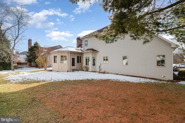 snow covered back of property with entry steps and a lawn