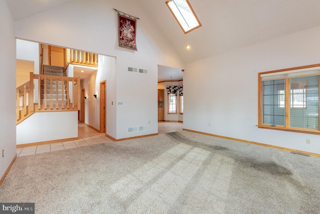 unfurnished living room featuring light tile patterned floors, light carpet, a skylight, visible vents, and stairs