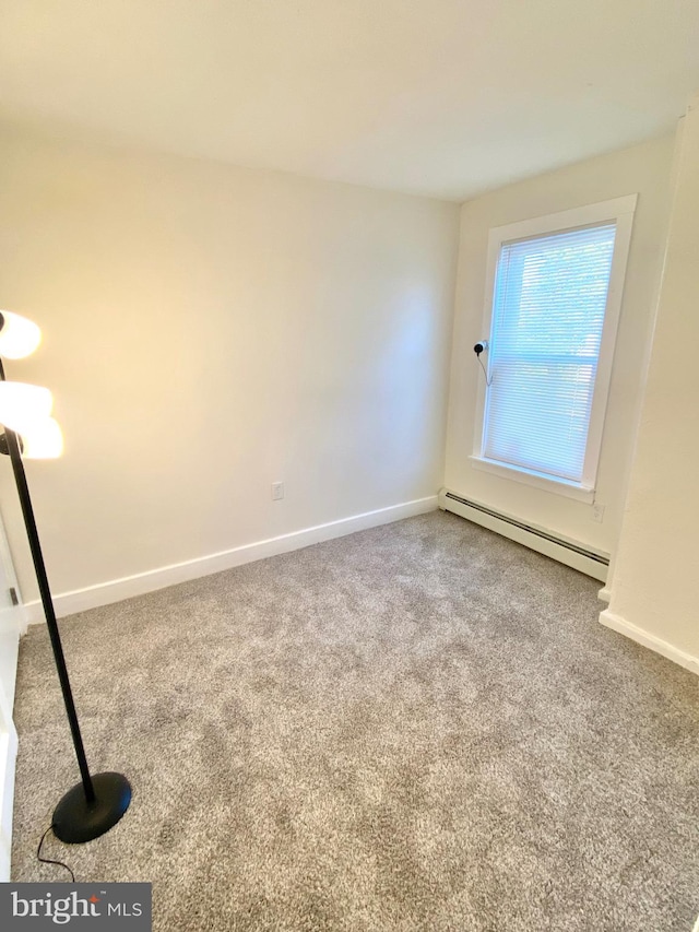 unfurnished room with carpet flooring and a baseboard heating unit