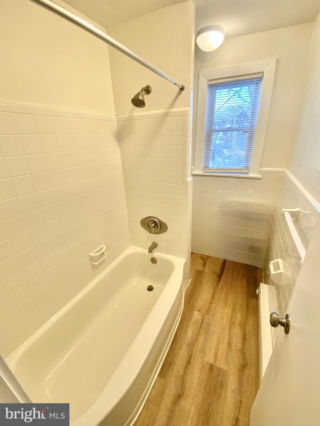 bathroom featuring hardwood / wood-style floors, tiled shower / bath combo, and tile walls