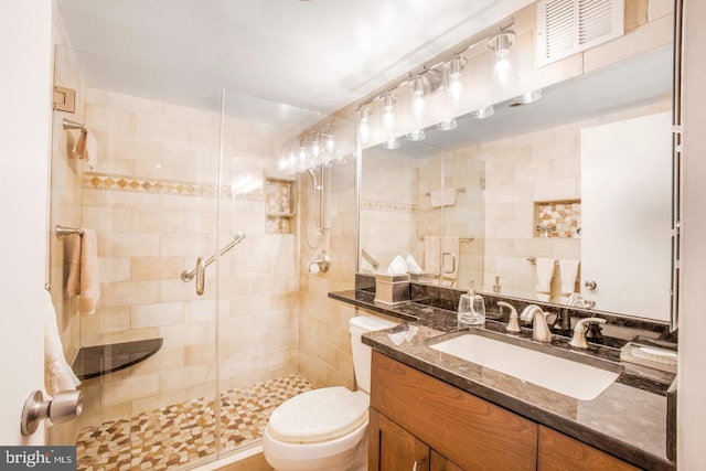 bathroom with toilet, an enclosed shower, and vanity