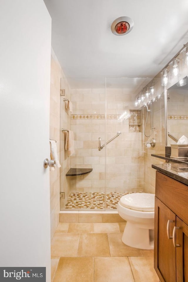 bathroom featuring toilet, a shower with door, and vanity