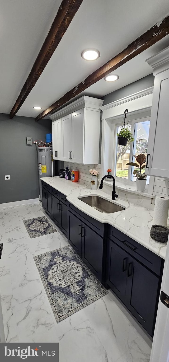 kitchen featuring light stone counters, backsplash, beamed ceiling, sink, and white cabinetry