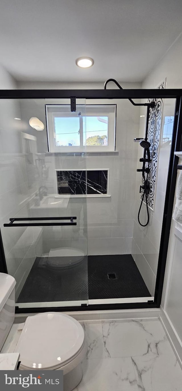 bathroom with toilet and a shower with door