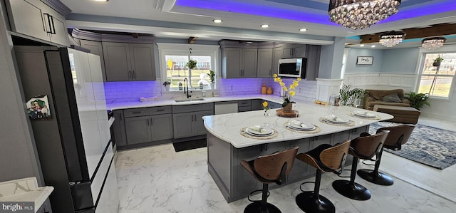 kitchen featuring gray cabinetry, hanging light fixtures, plenty of natural light, sink, and fridge