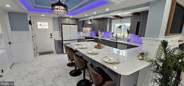 kitchen with kitchen peninsula, a breakfast bar, white fridge, light stone counters, and pendant lighting