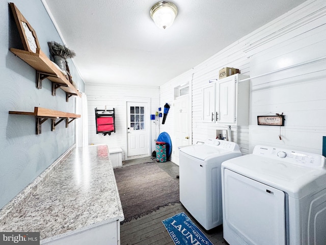 laundry room featuring washer and dryer, cabinets, and wood walls