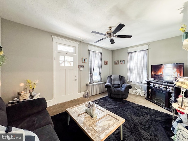 living room featuring carpet floors, ceiling fan, radiator heating unit, and a textured ceiling