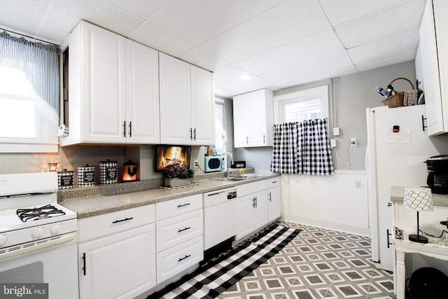 kitchen featuring white cabinetry, a drop ceiling, and white appliances