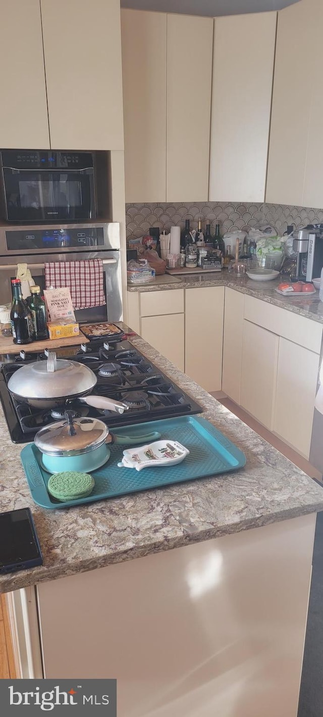 kitchen with light stone counters, backsplash, and oven