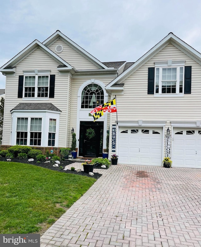 view of property featuring a garage and a front lawn