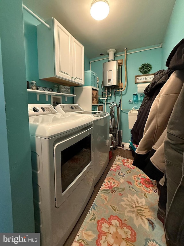 laundry area with cabinets, dark hardwood / wood-style floors, tankless water heater, and independent washer and dryer