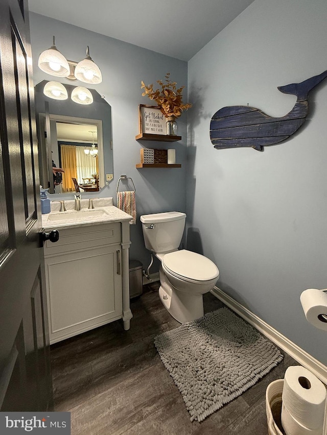 bathroom featuring hardwood / wood-style flooring, toilet, vanity, and a notable chandelier