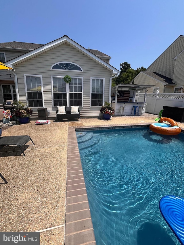 view of pool featuring exterior bar and a patio