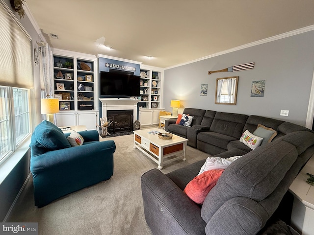 carpeted living room featuring built in shelves, ornamental molding, and a healthy amount of sunlight