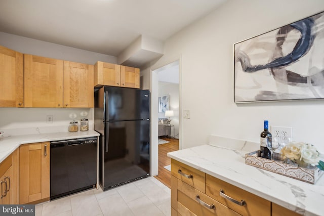 kitchen featuring light stone countertops, light brown cabinets, and black appliances