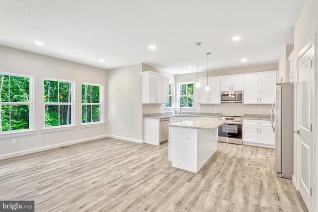 kitchen with stainless steel appliances, white cabinetry, a kitchen island, and decorative light fixtures