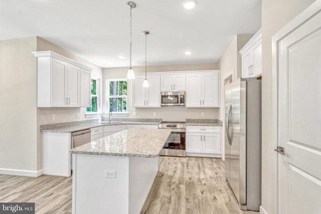 kitchen featuring pendant lighting, a kitchen island, white cabinetry, stainless steel appliances, and sink