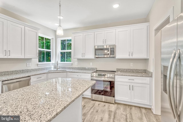 kitchen featuring appliances with stainless steel finishes, sink, white cabinetry, and decorative light fixtures