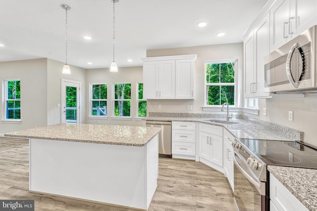 kitchen with decorative light fixtures, a center island, sink, appliances with stainless steel finishes, and white cabinets