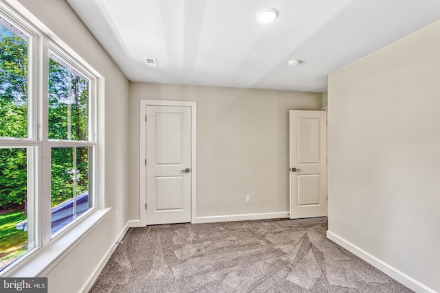 spare room featuring light colored carpet and plenty of natural light