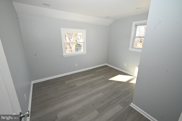 spare room featuring dark hardwood / wood-style floors and lofted ceiling