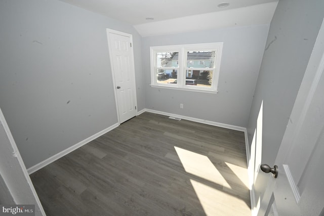 unfurnished room with dark hardwood / wood-style floors and vaulted ceiling