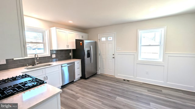 kitchen with tasteful backsplash, white cabinetry, sink, and stainless steel appliances