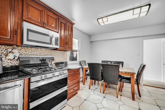 kitchen featuring decorative backsplash, dark stone countertops, and stainless steel appliances