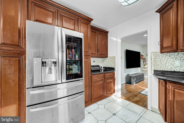 kitchen featuring stainless steel fridge, dark stone countertops, and backsplash